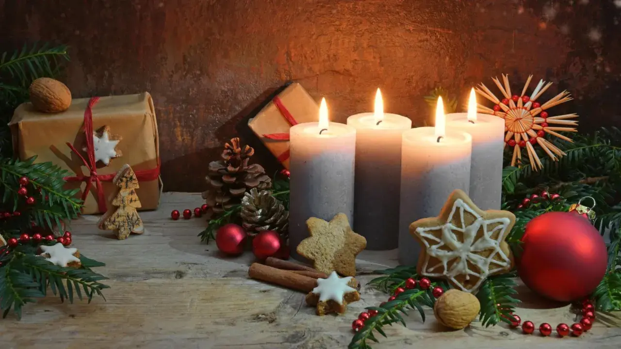 Vier brennende Kerzen im **Hintergrund Adventszeit**, umgeben von Tannenzweigen, Geschenken, Nüssen und Weihnachtsplätzchen.
