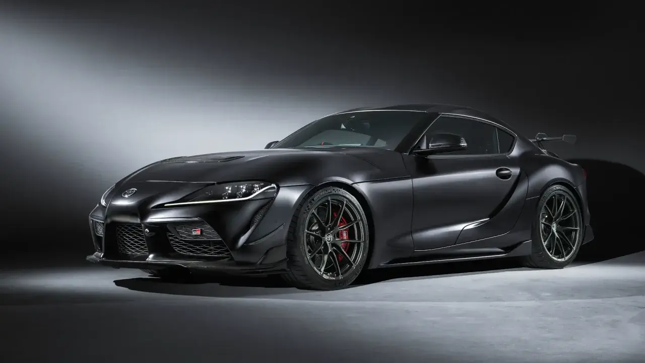 Matowa czerń podkreśla agresywną sylwetkę sportowego coupe Toyota GR Supra. Widoczne czerwone zaciski hamulcowe i aerodynamiczne dodatki.