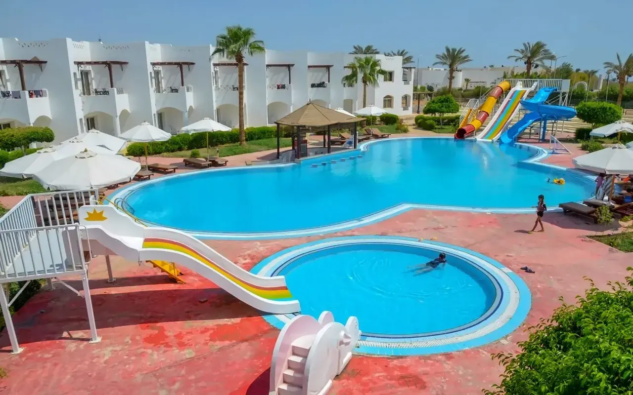 Egipt last minute all inclusive najtaniej: basen z wodnymi zjeżdżalniami i palmami, idealny na wakacje.
