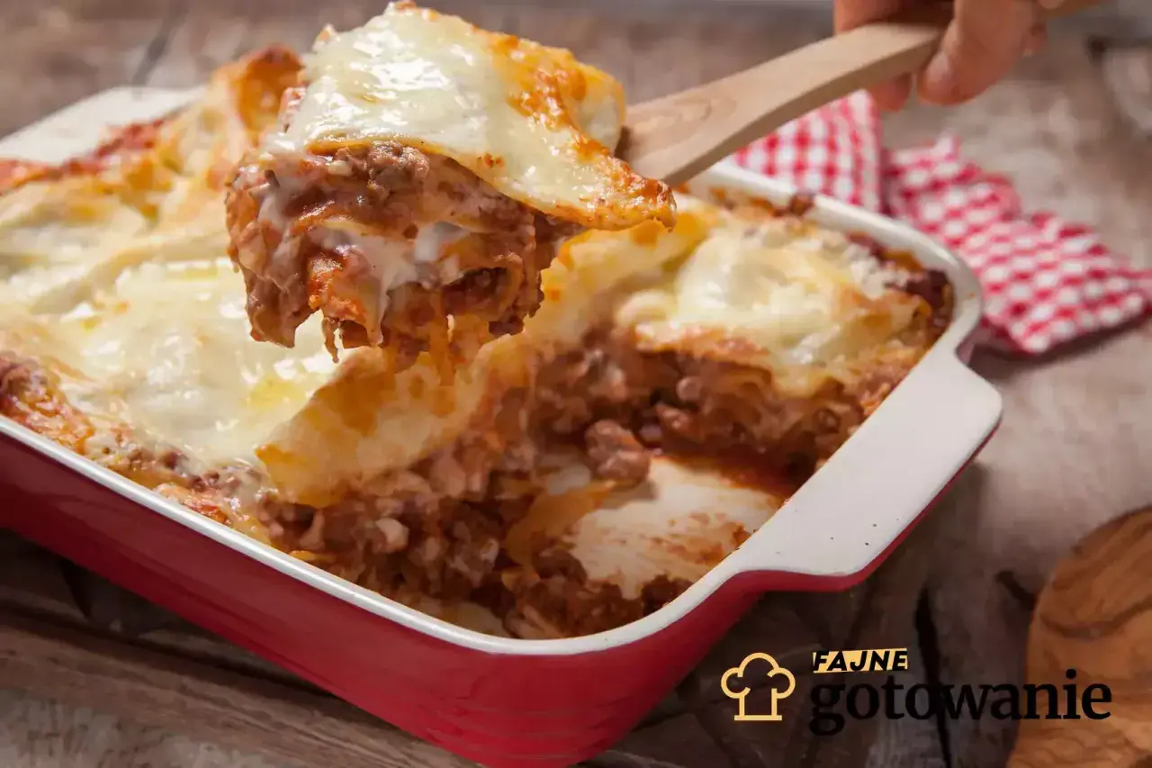 Pyszna, gorąca lasagne z mięsem mielonym i ciągnącym serem, właśnie nakładana drewnianą łopatką. Idealna na rodzinny obiad.