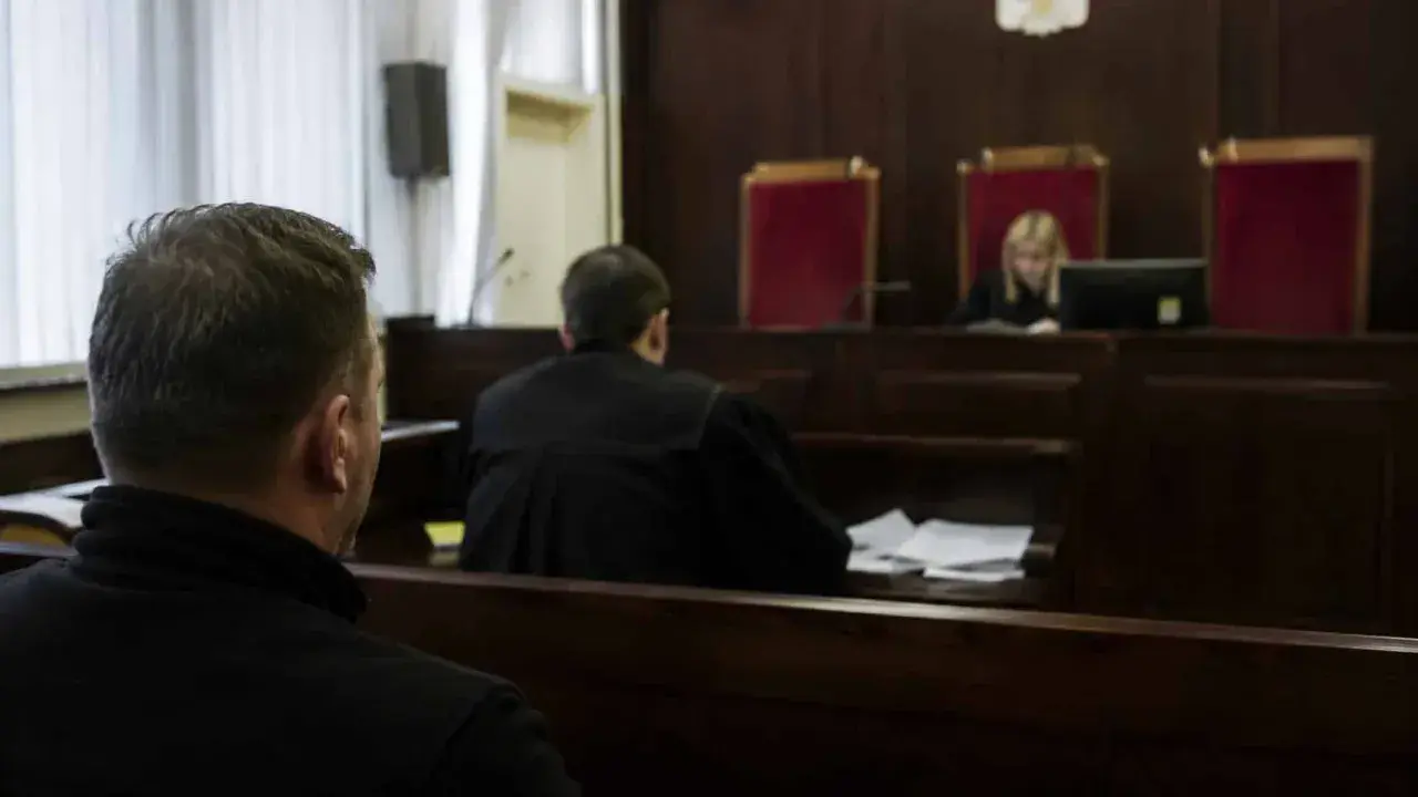 W sali sądowej mężczyzna czeka na rozprawę. Ile trwa sprawa karna?
