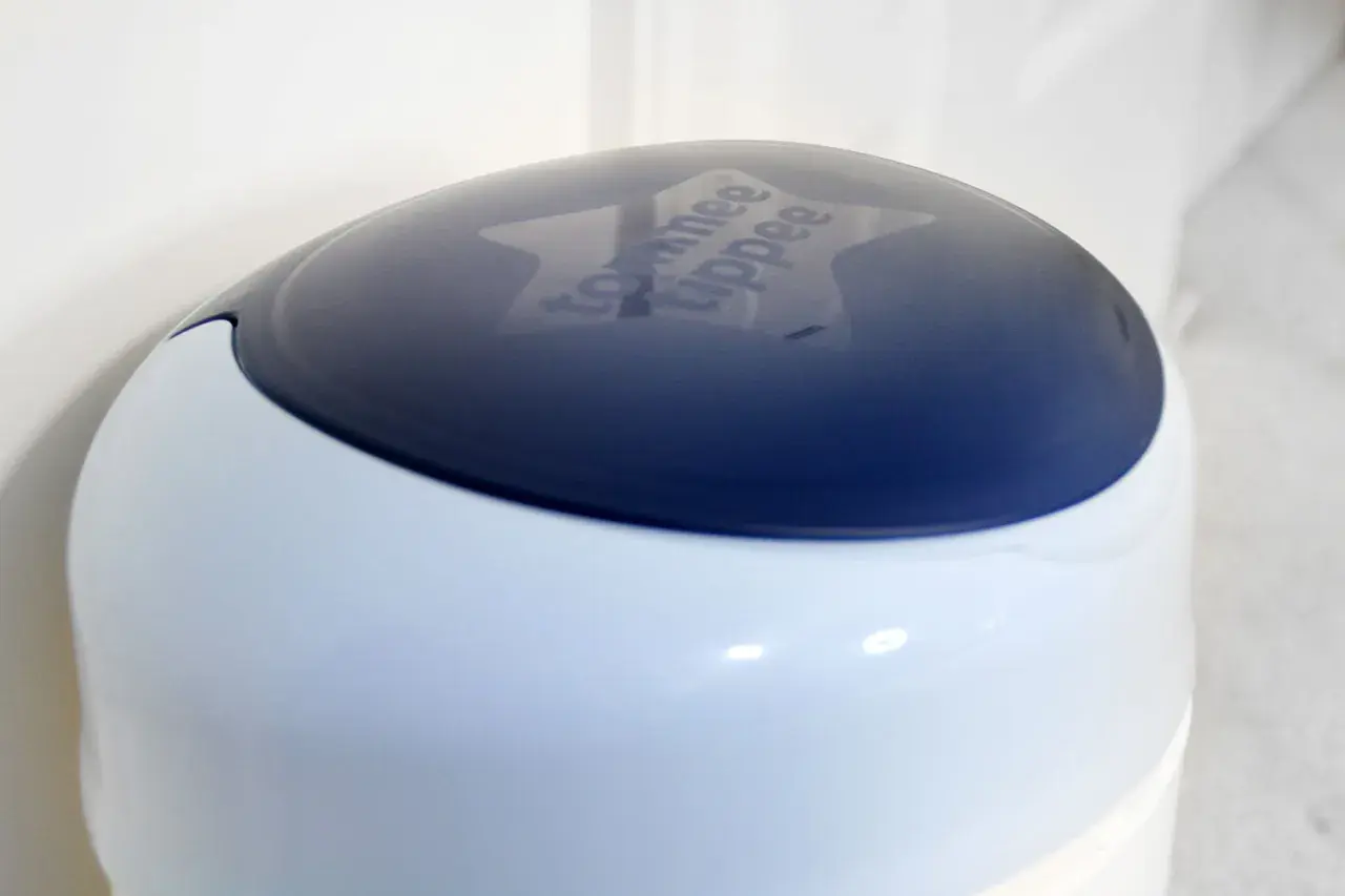 Niebieska pokrywa kosza na pampersy Tommee Tippee z wygrawerowanym logo.