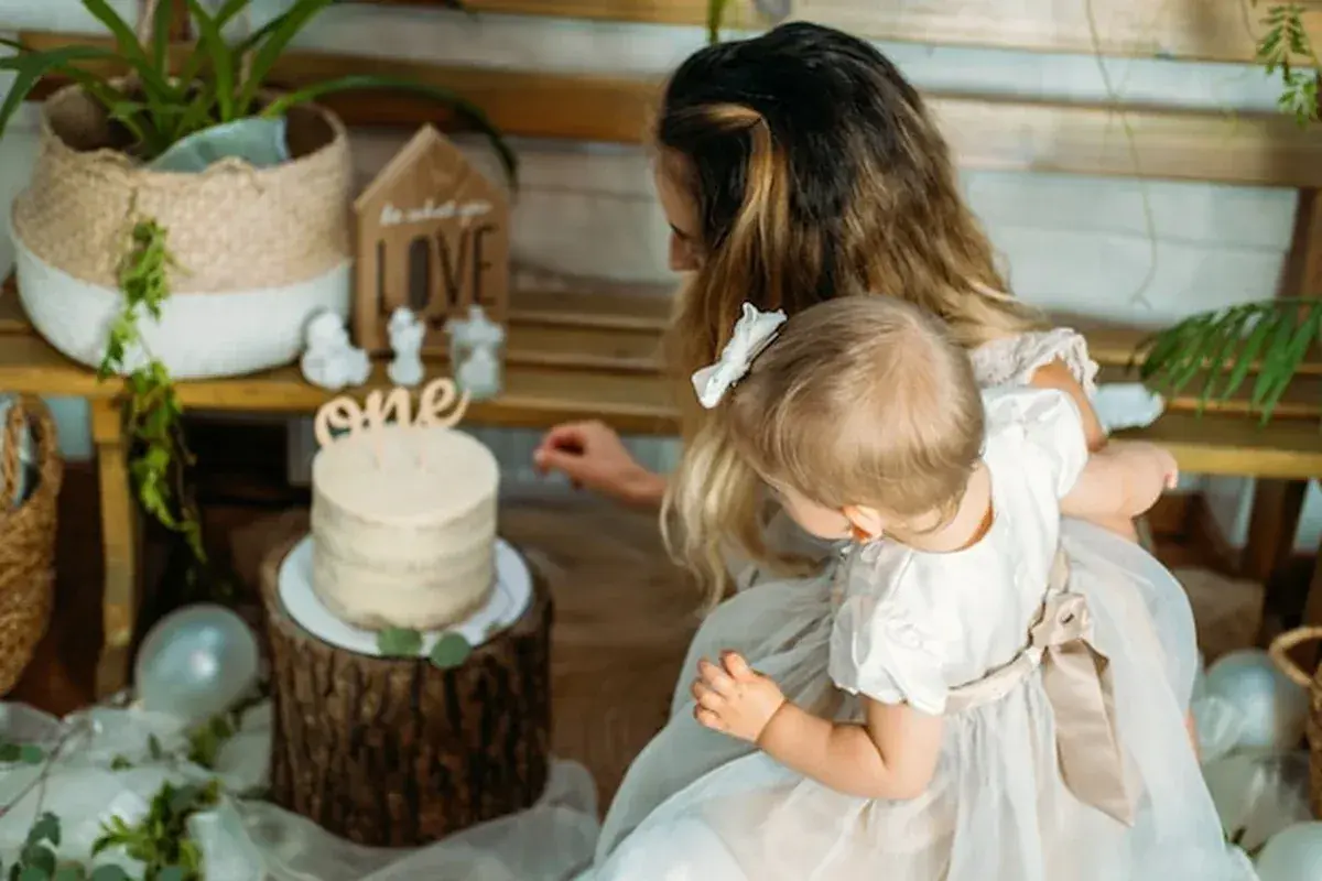 Mama z córką przy torcie na roczek. Piękny tort i dekoracje, idealne na prezent, co kladzie sie dziecku do wyboru na roczek.