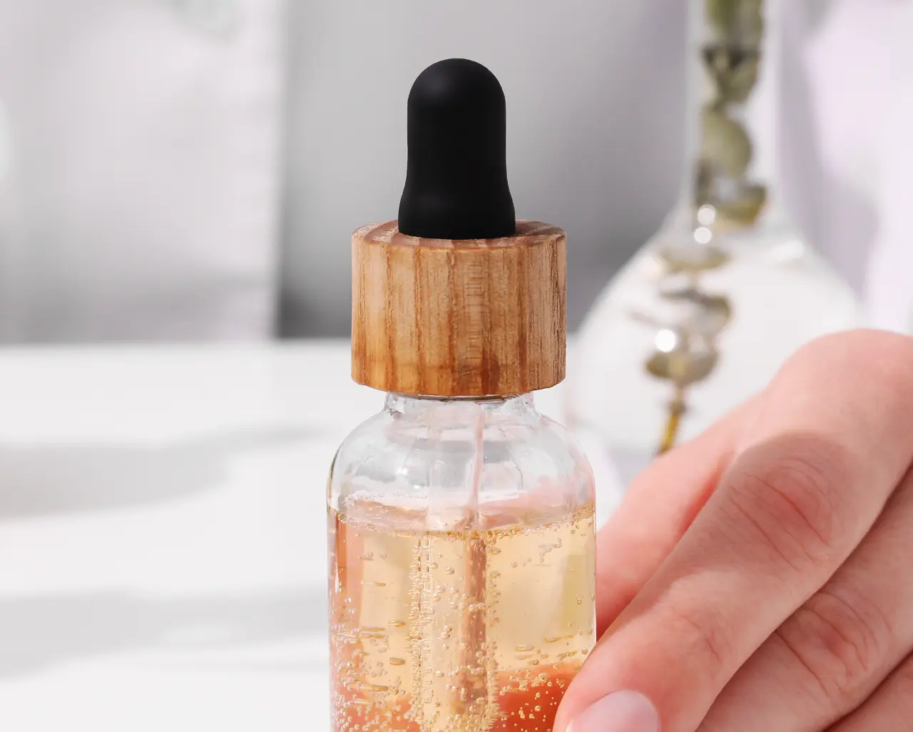 Dłoń trzymająca serum z pipetką. Składniki takie jak EDTA w kosmetykach pomagają stabilizować formuły.