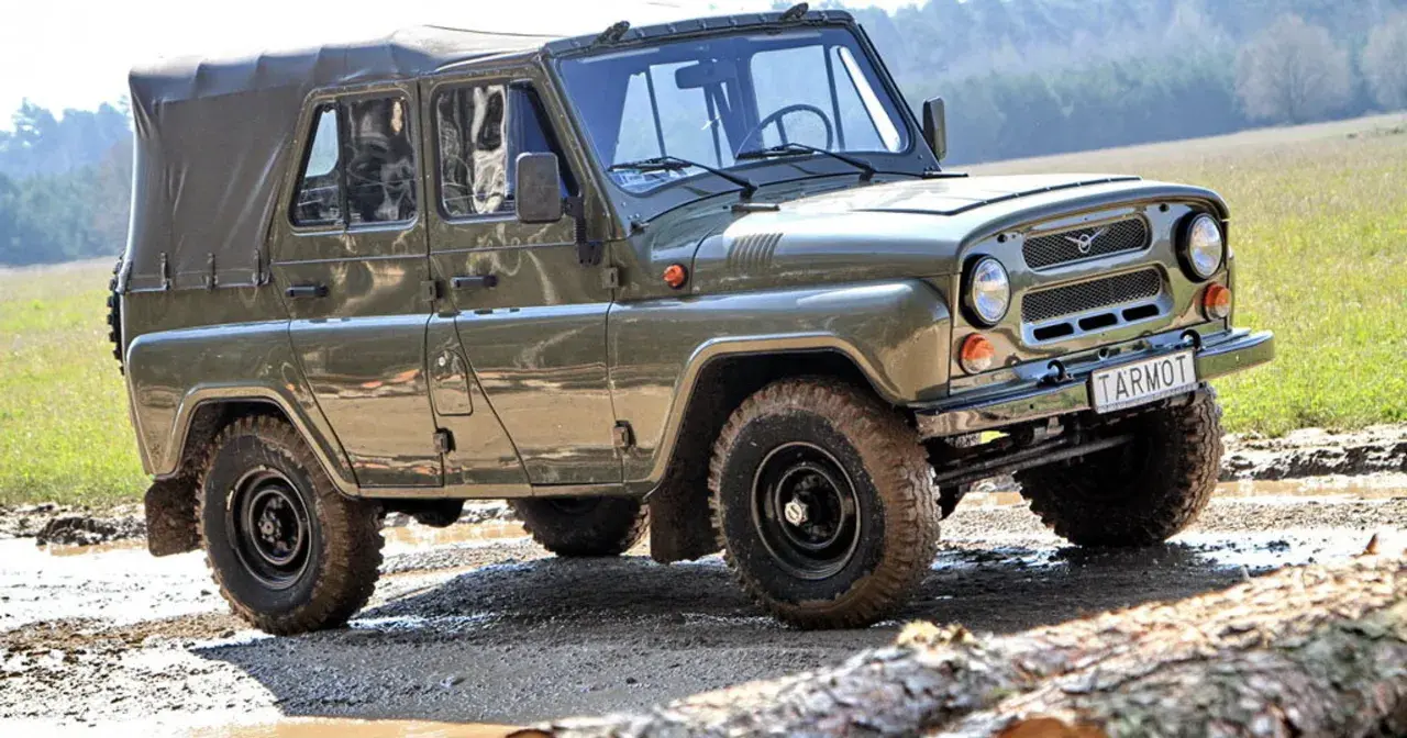 Zielony UAZ z plandeką, marka samochodu na u, pokonuje błotnisty teren.