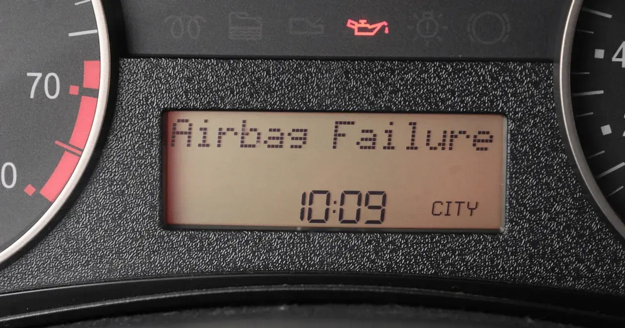 Na desce rozdzielczej świeci się kontrolka poduszki powietrznej z napisem "Airbag Failure". Obok widnieje godzina 10:09 i napis CITY.