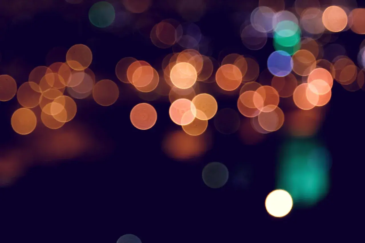 Rozmyte, okrągłe światła tworzą magiczny **bokeh** na ciemnym tle.
