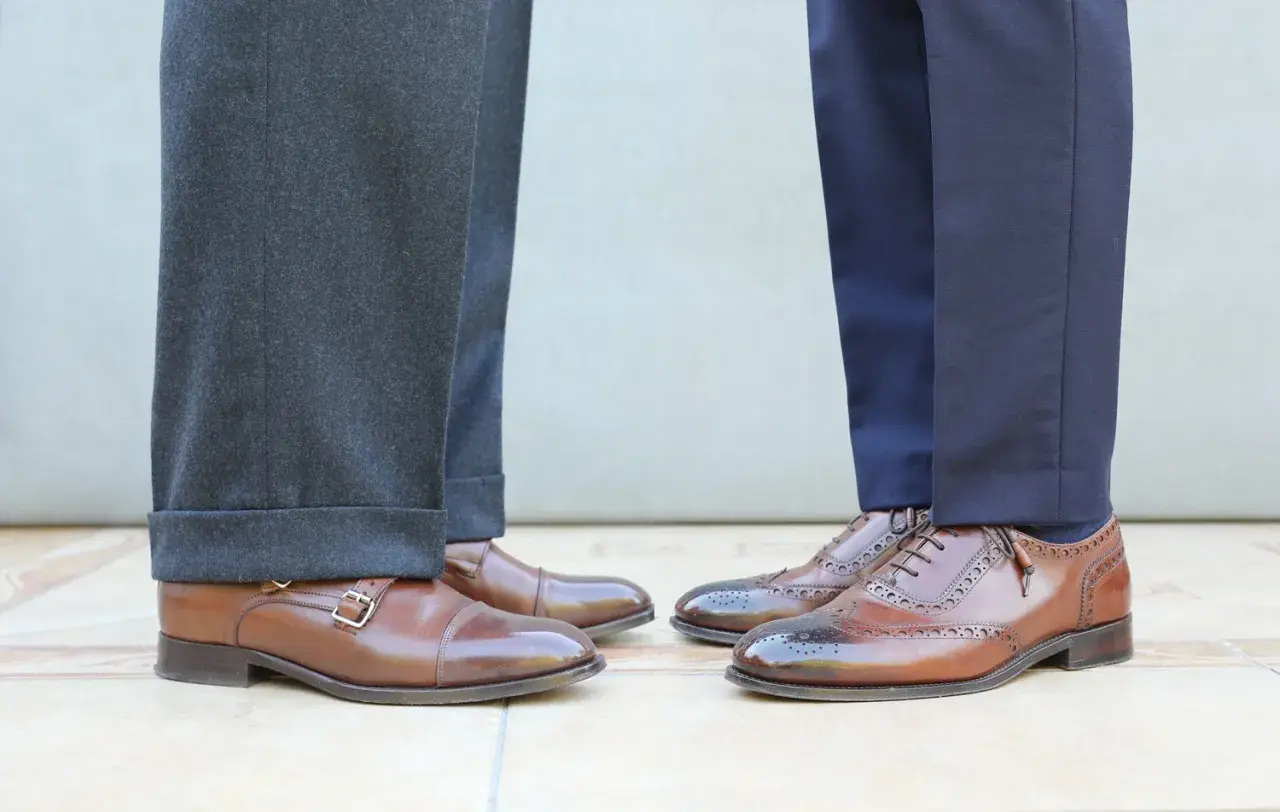 Długość spodni garniturowych: jeden model ma wywinięte nogawki, drugi gładkie. Eleganckie buty męskie.