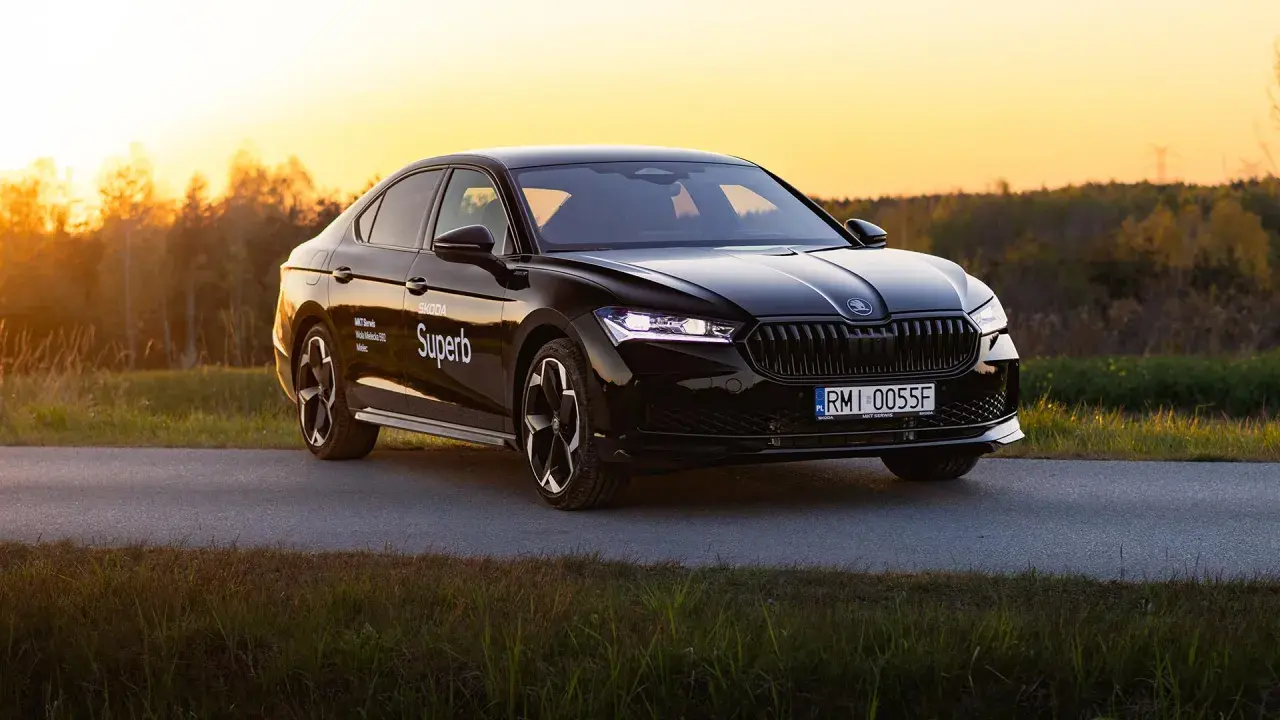 Czarny Skoda Superb 4 na tle zachodzącego słońca. Elegancki sedan z nowoczesnymi światłami i felgami.