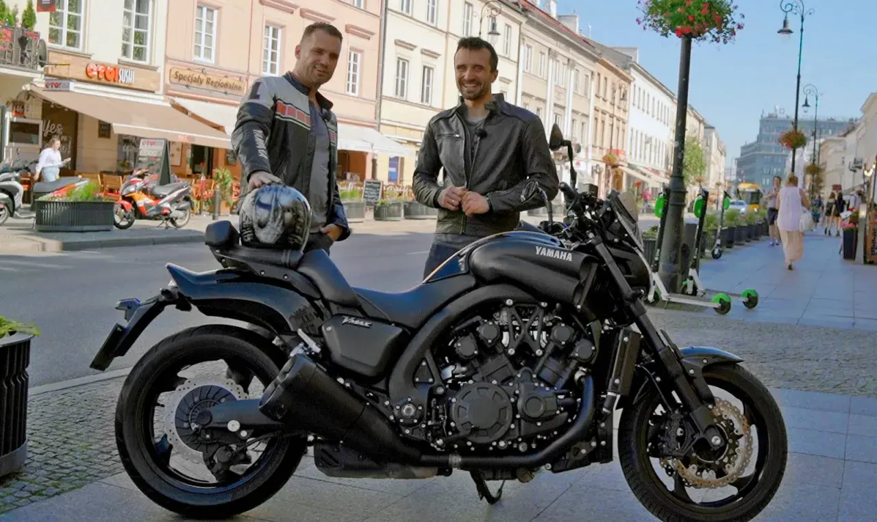 Dwóch mężczyzn pozuje obok czarnego motocykla Yamaha V-Max 1700 na ulicy.