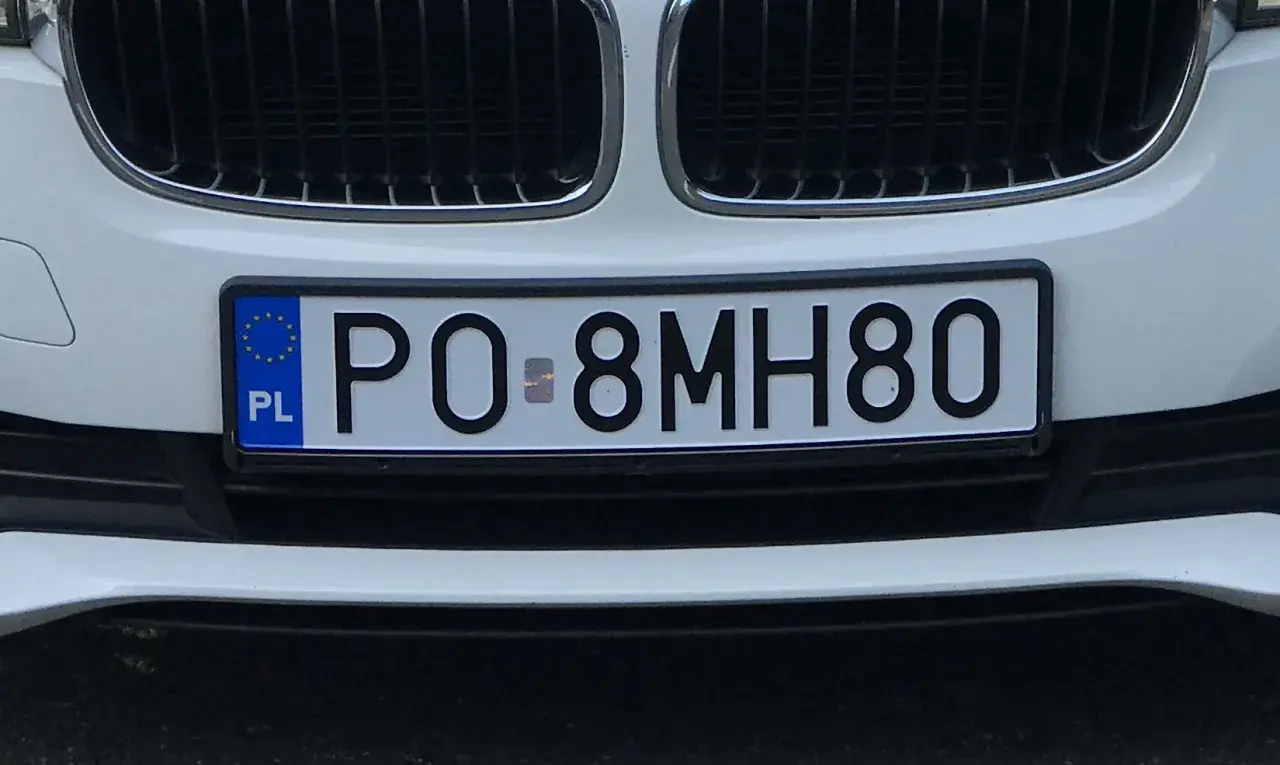 Białe BMW z tablicą rejestracyjną PO 8MH80.