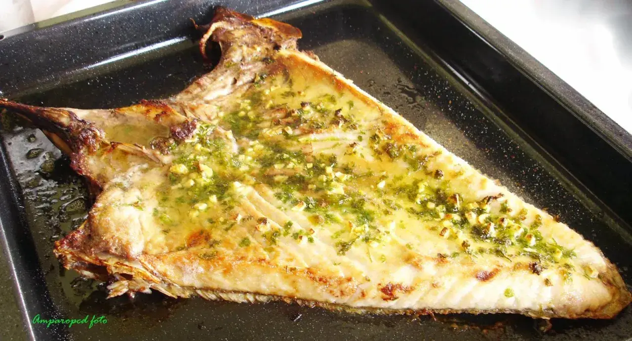 Deliciosa ventresca al horno, dorada y jugosa, con un aderezo de ajo y perejil que invita a probarla.