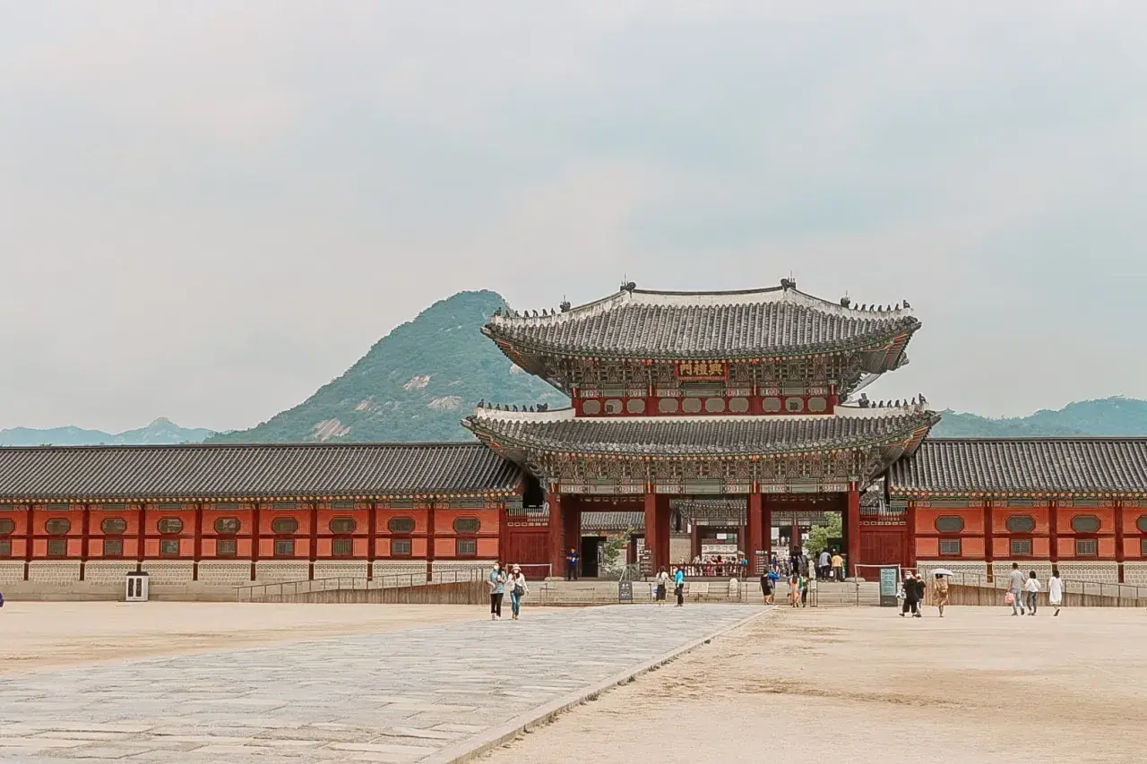 Zwiedzający pałac w Seulu, podziwiający architekturę. Czy Korea Południowa jest bezpieczna? Tak, to kraj przyjazny turystom.