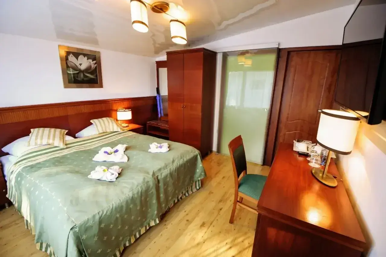 Przytulny pokój hotelowy z dużym łóżkiem, szafą i biurkiem. Czy żeby wynająć pokój w hotelu trzeba mieć 18 lat?