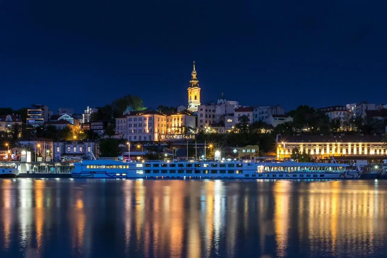 Nocny Belgrad z rzeką i statkiem wycieczkowym. Czy do Serbii potrzebny jest paszport? Sprawdź przed podróżą!