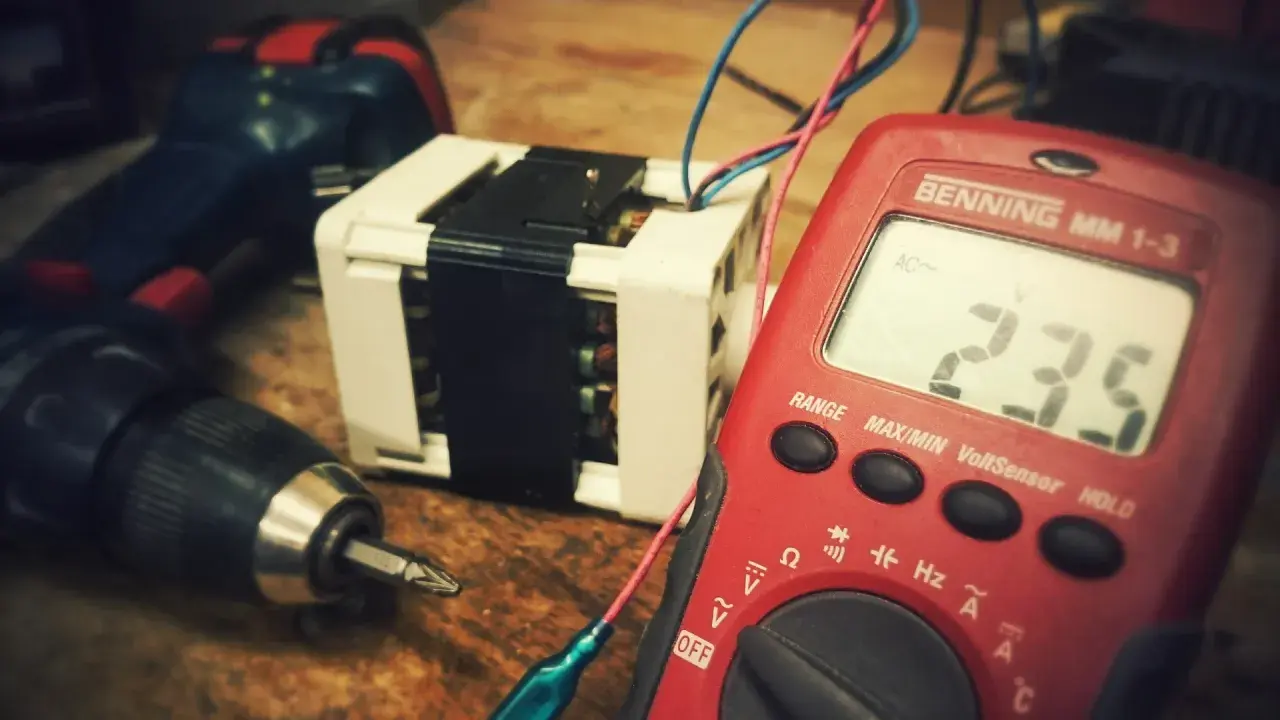 Narzędzia i transformator, potencjalne odpady elektroniczne, czekają na diagnozę multimetrem.