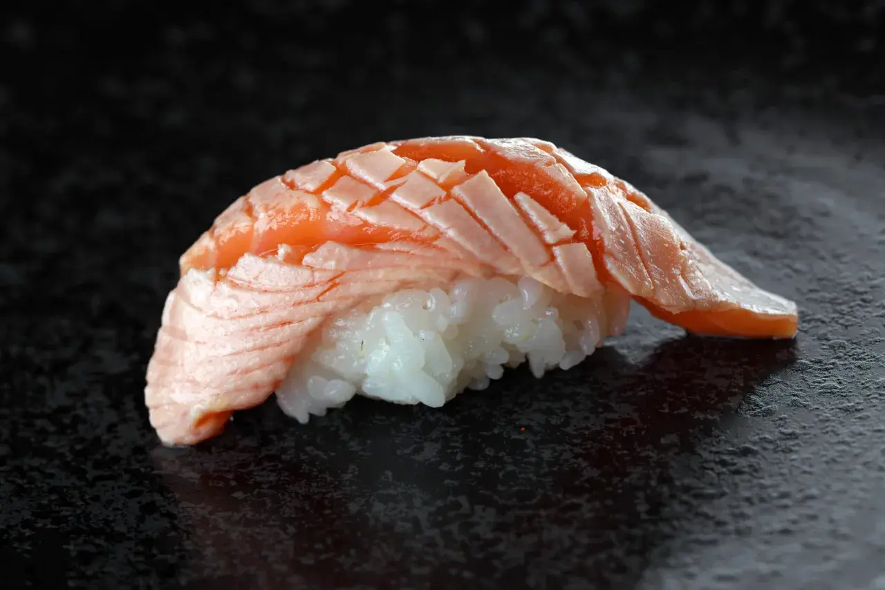 Jak wygląda sushi: delikatny ryż i soczysty, lekko opalony łosoś ułożony w wachlarz.