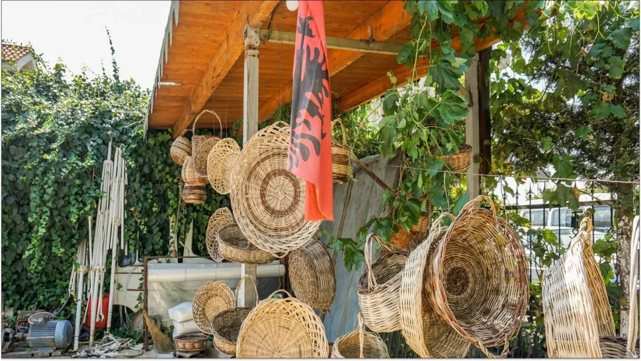 Wiele koszy z wikliny wisi pod zadaszeniem, obok albańskiej flagi. Czy Albania jest bezpieczna dla kobiet? Tak, to piękny kraj.