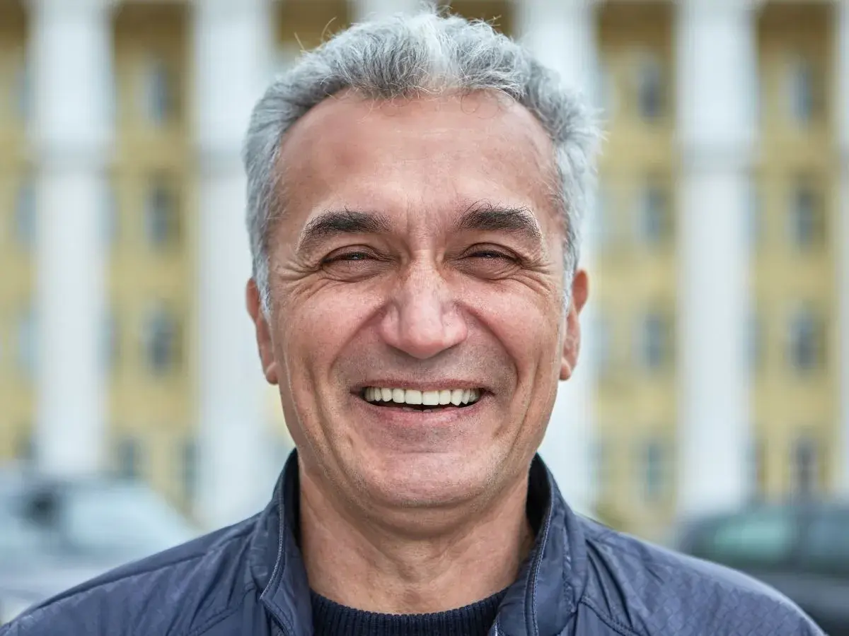 Uśmiechnięty mężczyzna z siwymi włosami, który wygląda jak typowy boomer. Co to znaczy? To ktoś z pokolenia wyżu demograficznego, często kojarzony z pewnymi wartościami i stylem życia.
