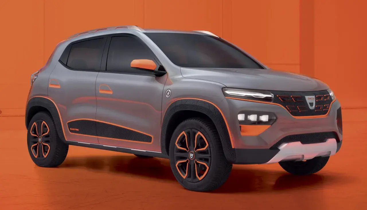 Szary samochód Dacia Spring z pomarańczowymi akcentami na tle pomarańczowym.