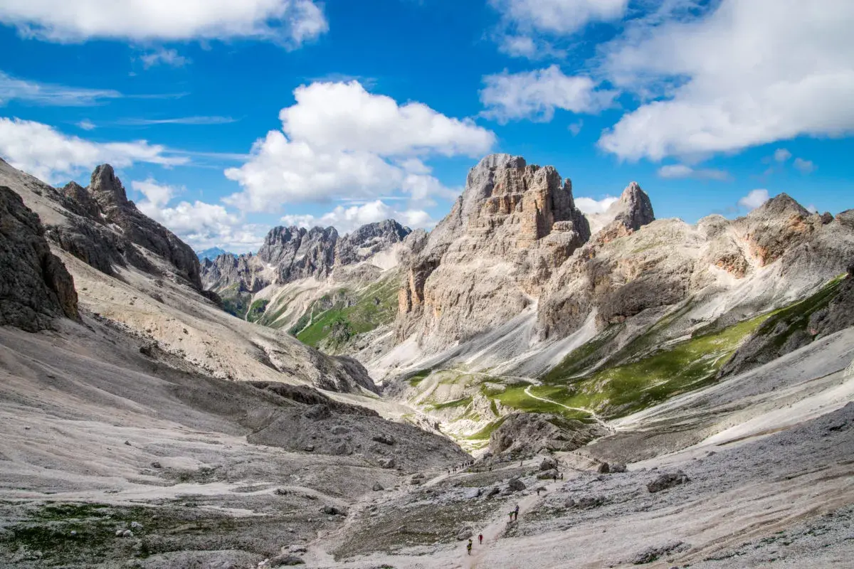 Malownicze **Val di Fassa** w Dolomitach. Kręta ścieżka prowadzi przez skaliste zbocza i zielone hale ku majestatycznym szczytom.