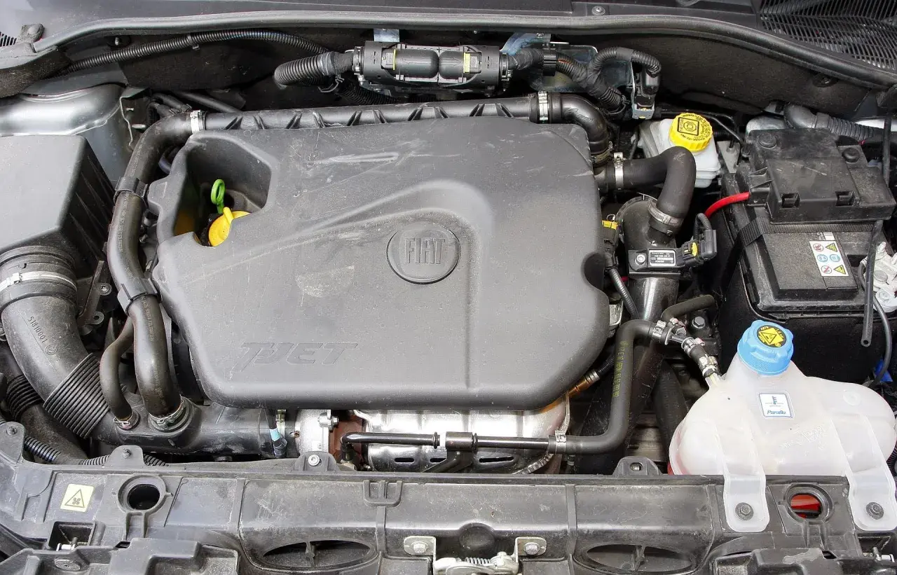 Silnik 1.4 z Fiata Grande Punto. Widoczny plastikowy kolektor, akumulator i zbiornik płynu chłodniczego.
