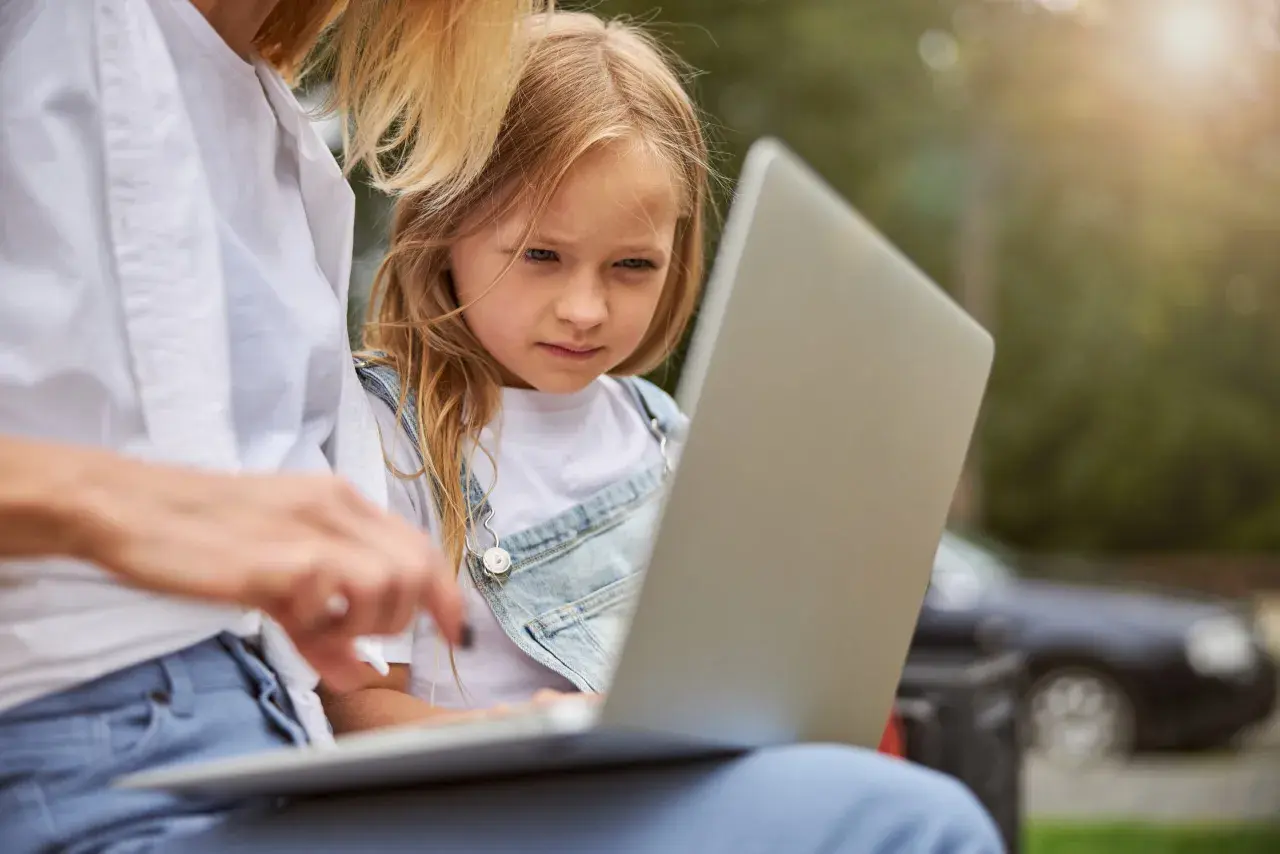Mama z córką przeglądają internet, szukając informacji, kiedy jest rekrutacja do żłobka.