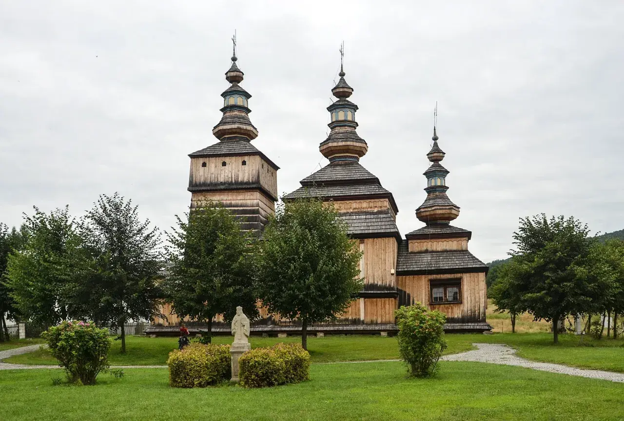Drewniana cerkiew z trzema kopułami, otoczona zielenią. Wspaniałe krempna atrakcje dla miłośników historii i architektury.