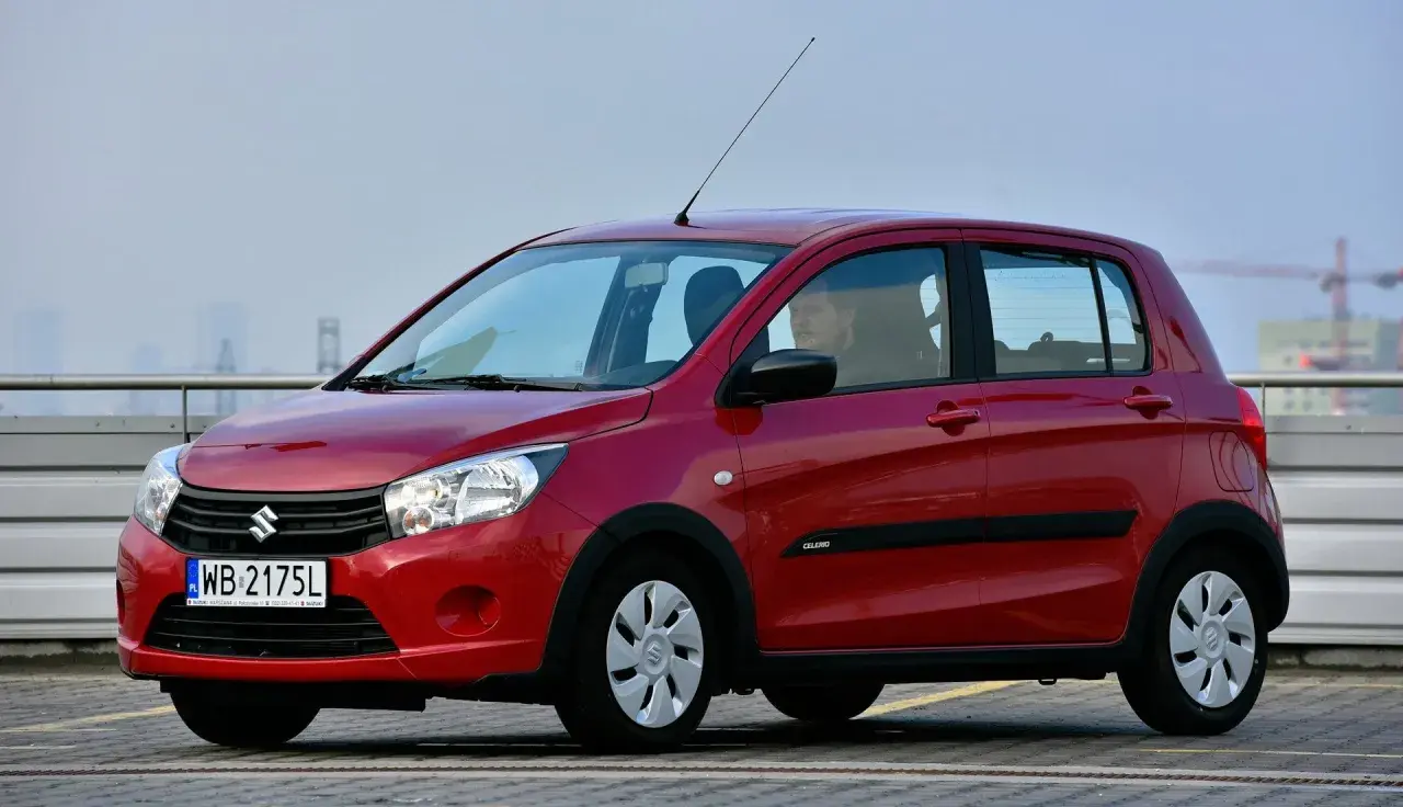 Czerwony Suzuki Celerio z polskimi tablicami rejestracyjnymi WB 2175L zaparkowany na zewnątrz.