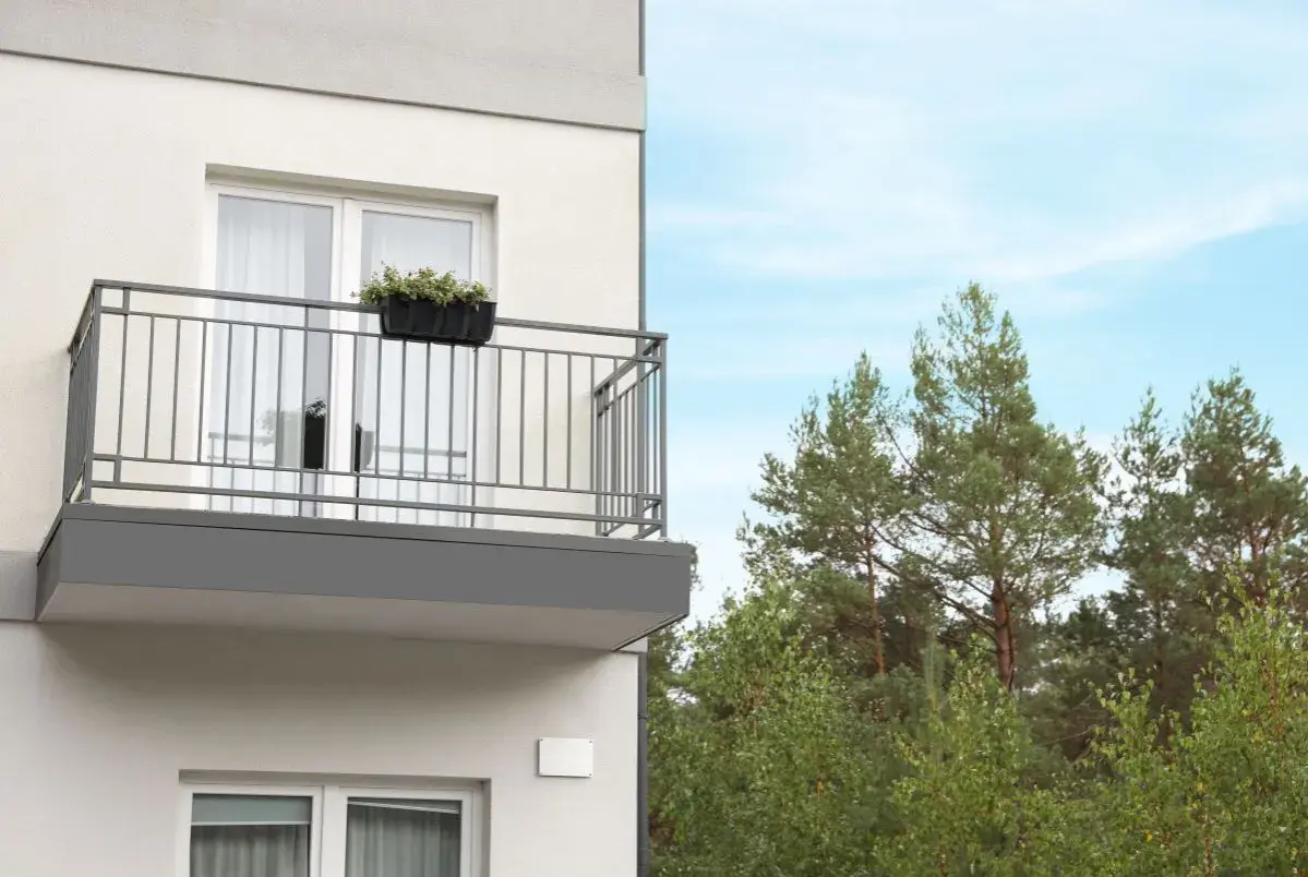 Nowy balkon z kwiatami, z którego roztacza się widok na las. Czy to miejsce wolne od podatku od balkonu?