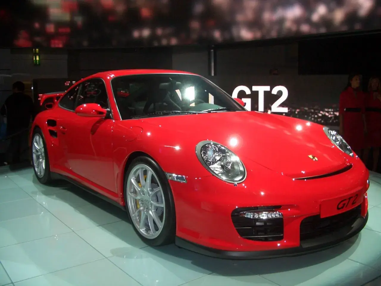 Czerwony Porsche 997 GT2 błyszczy na wystawie, gotowy do jazdy.