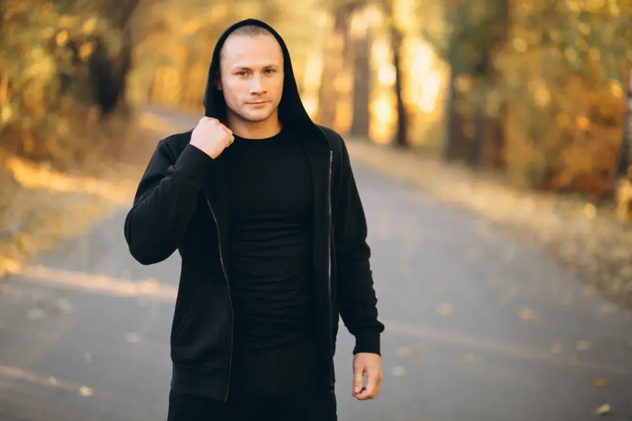 Mężczyzna w czarnej bluzie z kapturem i spodniami, idealny zestaw na fajne bluzy streetwear.