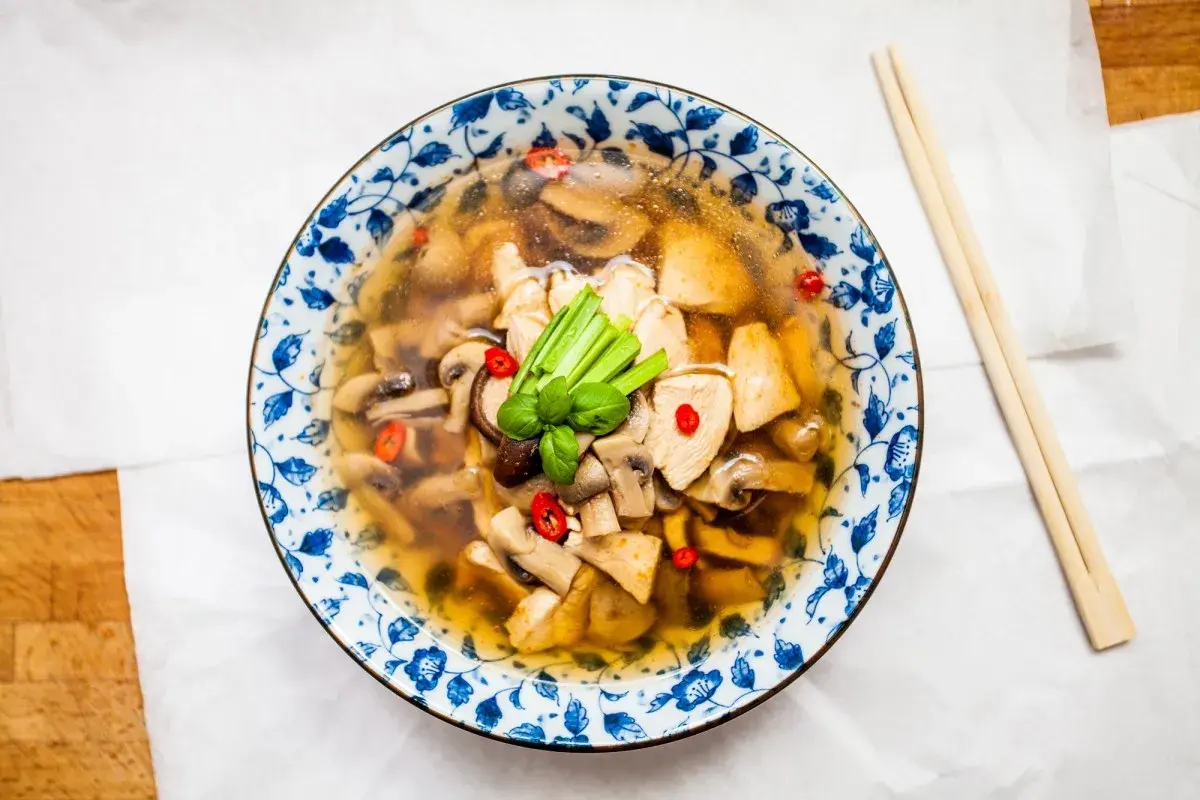 Aromatyczna zupa tom yum z kurczakiem i grzybami, ozdobiona chili i zieloną cebulką. Idealna na chłodne dni.