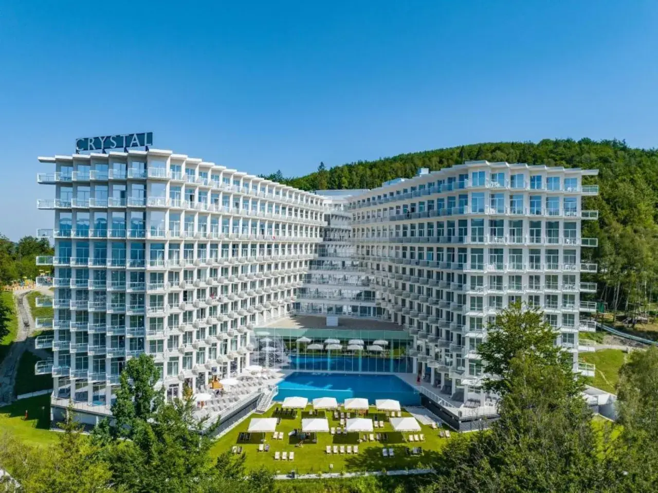 Nowoczesny hotel Crystal w Wiśle, z basenem i tarasami, otoczony zielenią. Idealne miejsce na górski relaks w Wiśle Mountain Spa.