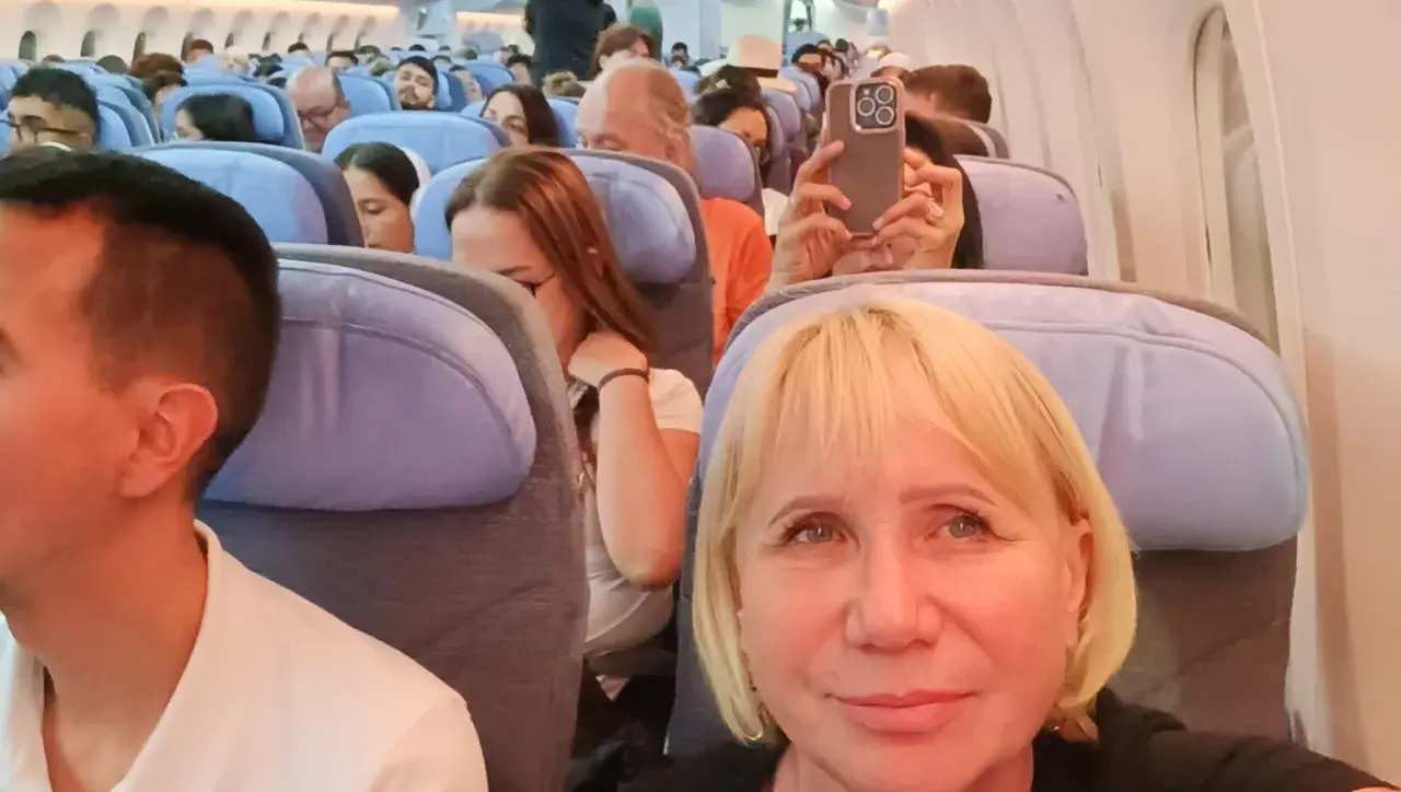 W samolocie, przygotowując się na najdłuższy lot samolotem, pasażerowie siedzą w rzędach. Kobieta robi zdjęcie telefonem.