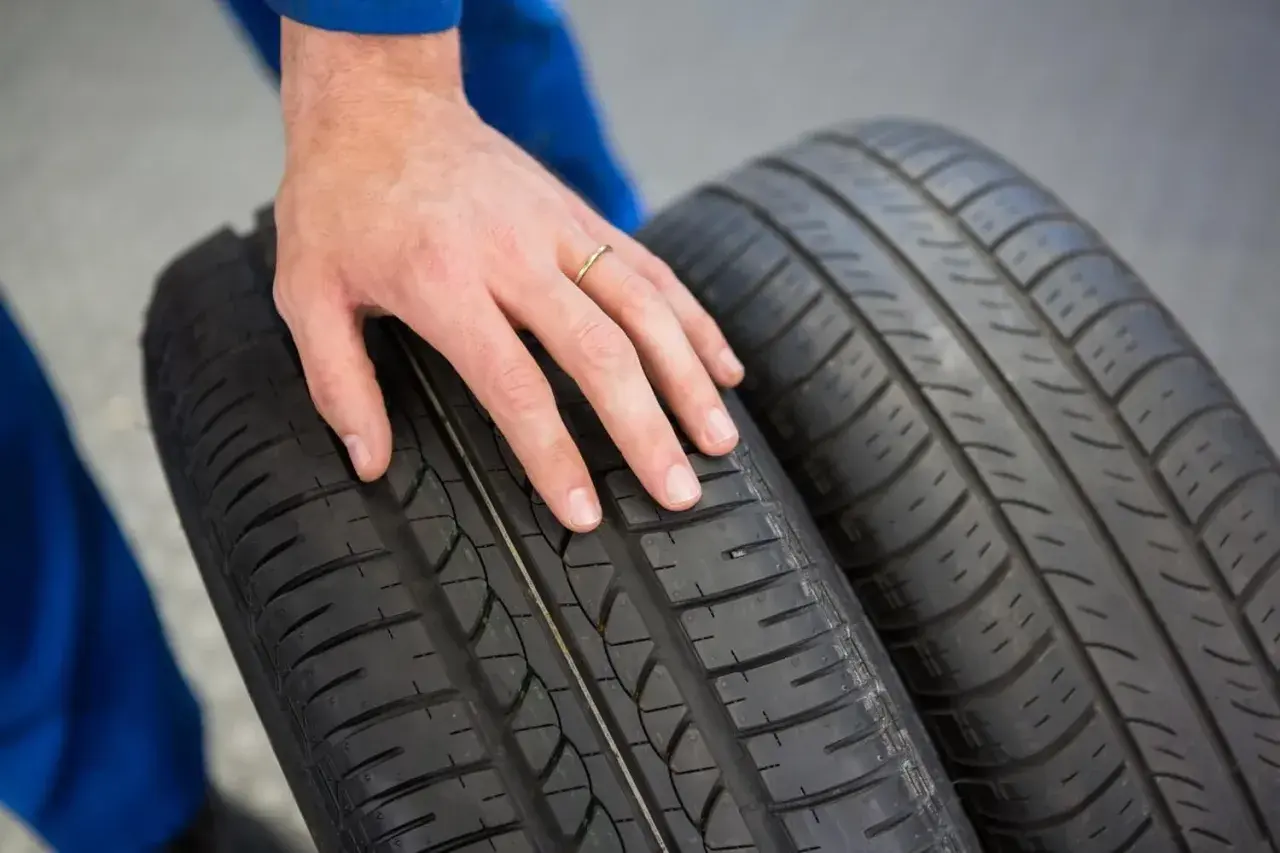 Dłoń mechanika dotyka bieżnika opony Hankook, sprawdzając jej stan. Dobre opony Hankook opinie to podstawa bezpiecznej jazdy.
