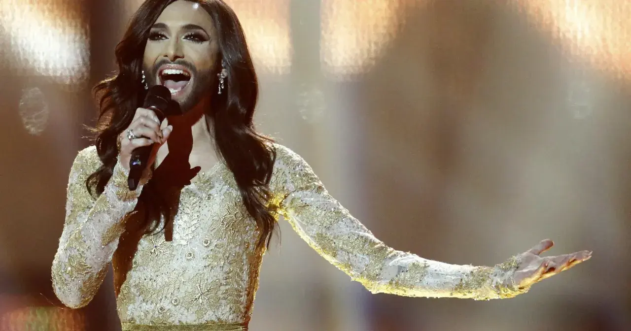 Conchita Wurst, zwyciężczyni Eurowizji, w złotej sukni z cekinami śpiewa na scenie.