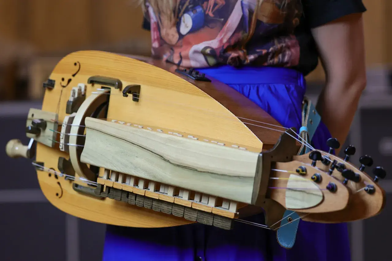 Drewniana lira korbowa, kozacki instrument muzyczny, z widocznymi strunami, klawiszami i korbą.