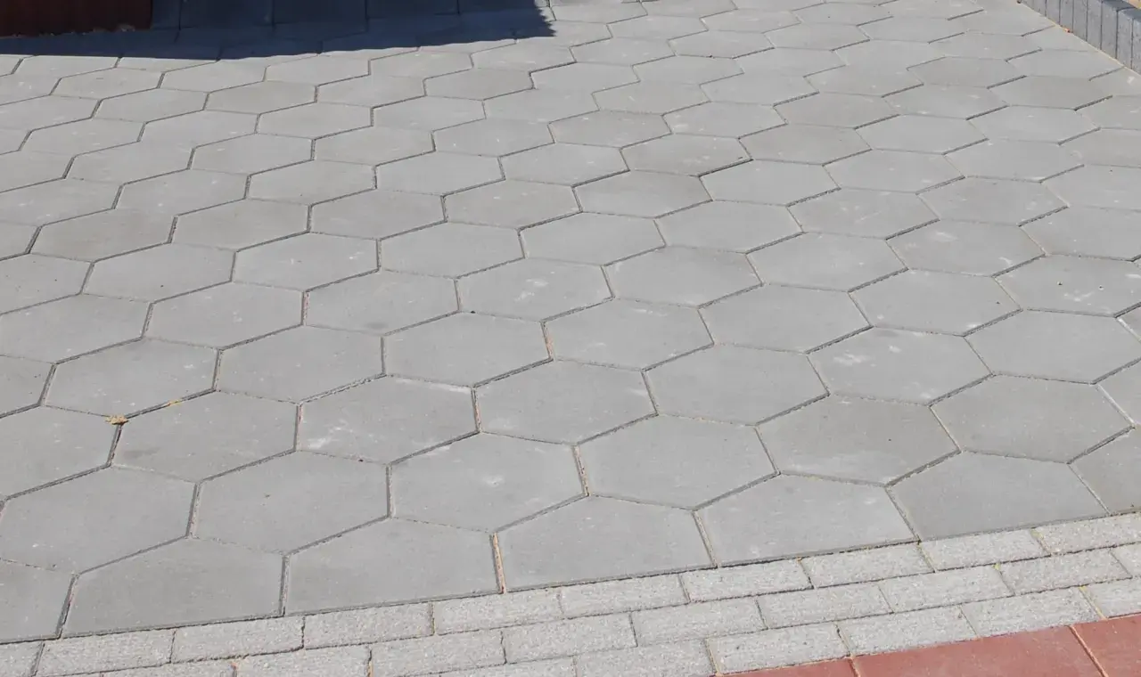 Szara, sześciokątna trelinka tworzy wzór na chodniku.
