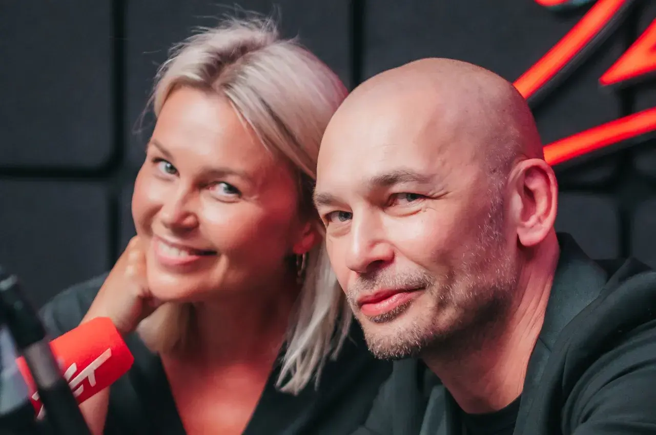 Tomasz Wygoda z żoną i dziećmi, uśmiechnięci przed mikrofonem.