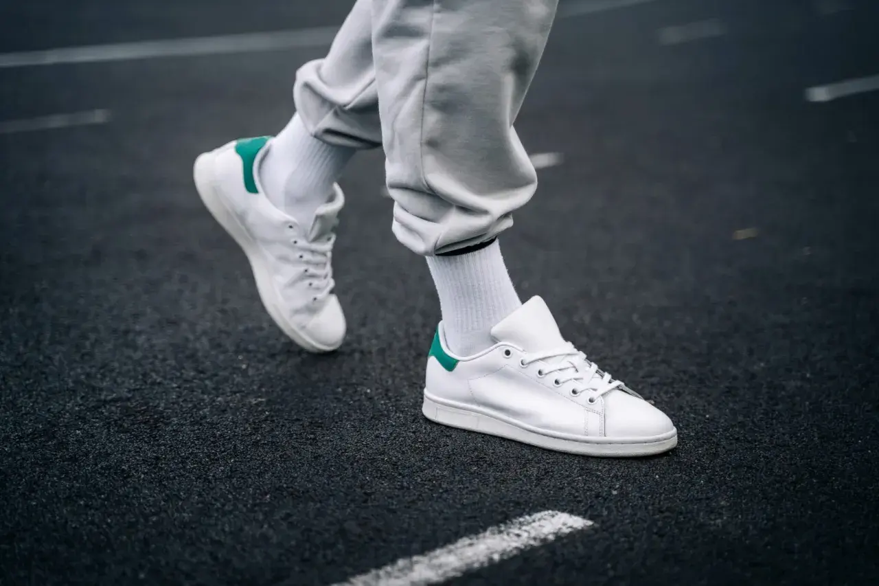 Un paio di sneakers bianche con dettagli verdi, simbolo di stile e comfort. Il loro significato va oltre la moda, rappresentando libertà di movimento.