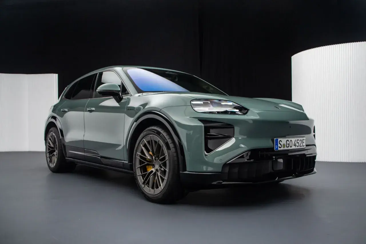 Zielony elektryczny Porsche Macan na ciemnym tle.
