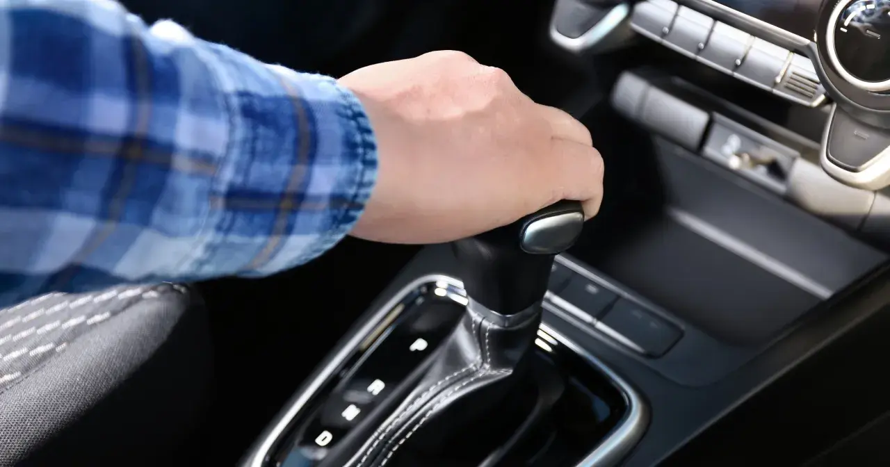 Dłoń na dźwigni zmiany biegów w aucie z funkcją auto hold i manualną skrzynią.