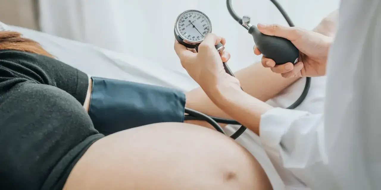 Lekarz mierzy ciśnienie w ciąży u ciężarnej kobiety. Monitorowanie ciśnienia jest kluczowe dla zdrowia mamy i dziecka.