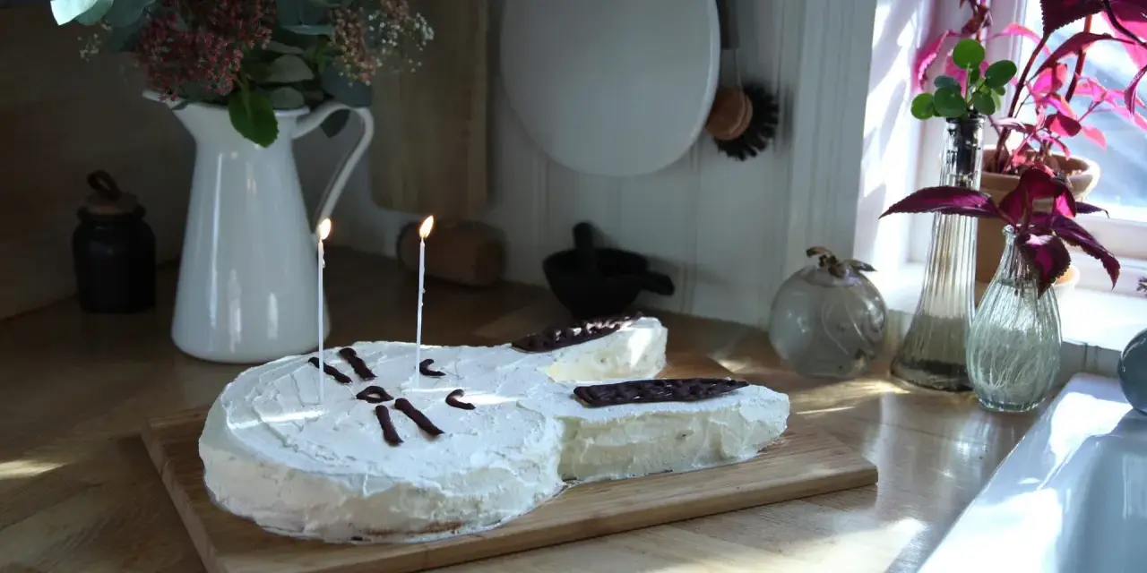 En gitarrformad tårta med vit frosting och chokladdekorationer, perfekt för alla musikälskare. En av många tårt ideer för en speciell dag.
