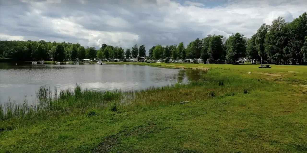 Vacker sjö vid Torsvikens camping med husbilar och träd.