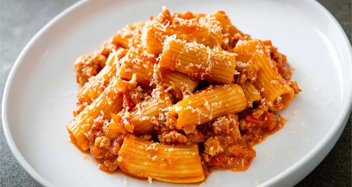 Un piatto invitante di pasta alla zozzona, con rigatoni conditi con un ricco ragù e abbondante parmigiano grattugiato.