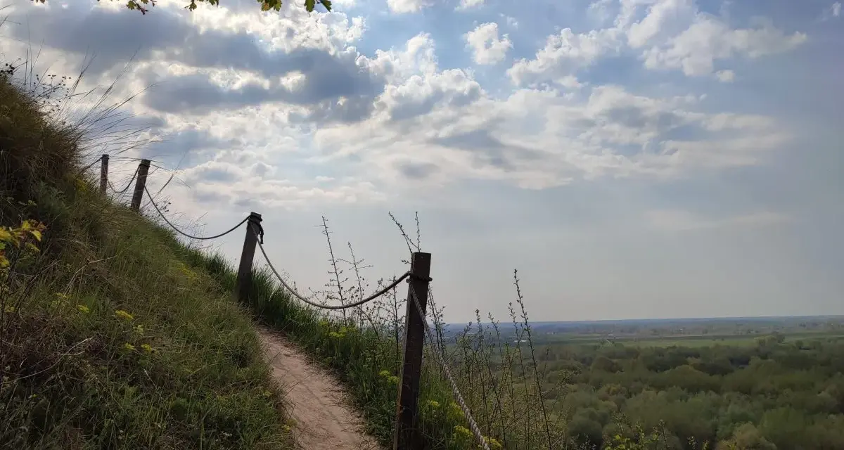 Ścieżka na zboczu Góry Pieprzowe. W oddali rozciąga się zielona dolina.