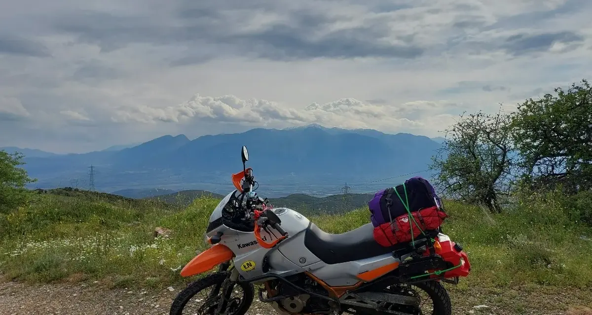 Motocykl gotowy na przygodę, z bagażami na wyprawę. Piękna grecja trasa z widokiem na góry.