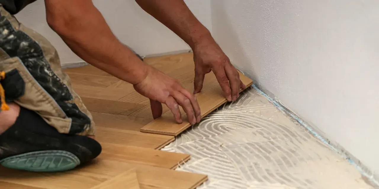 Manos colocando tablones de madera para un piso de parquet. Calculando el precio parquet piso 70m2.